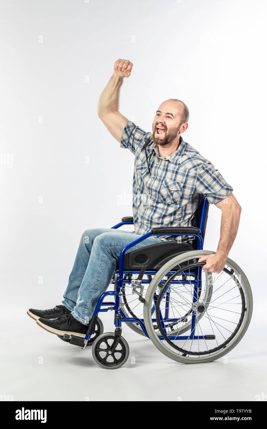 Homme handicapé sur fauteuil roulant avec bras levé en signe de victoire. Concept de défi et de positivité. Banque D'Images
