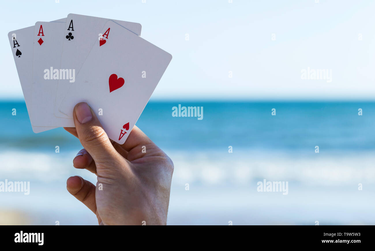 Jeu de carte Plein air à plage, quatre as dans la main du joueur avec fond de ciel et mer Banque D'Images