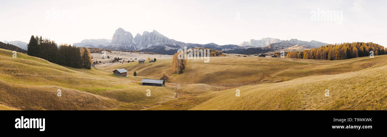 Belle vue sur la montagne chalets traditionnels en bois sur Scenic Alpe di Siusi célèbre Langkofel avec des pics de montagne dans l'arrière-plan dans la matinée d'or Banque D'Images
