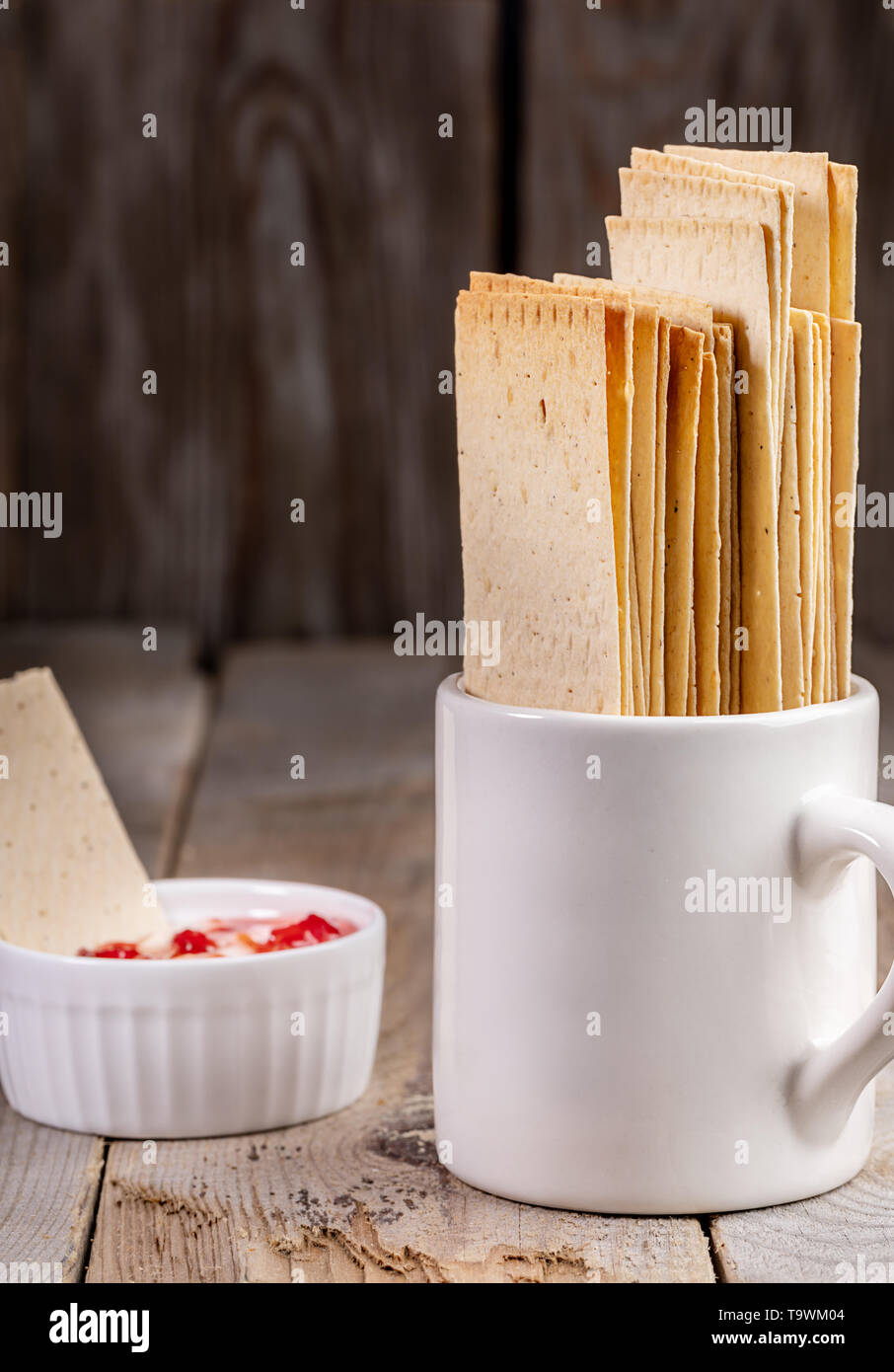 Mug blanc avec du blé crispbreads et petit bol en céramique avec de la crème et de la confiture de fraise sur l'ancienne rustique en arrière-plan. Snaks sain. Selective Banque D'Images