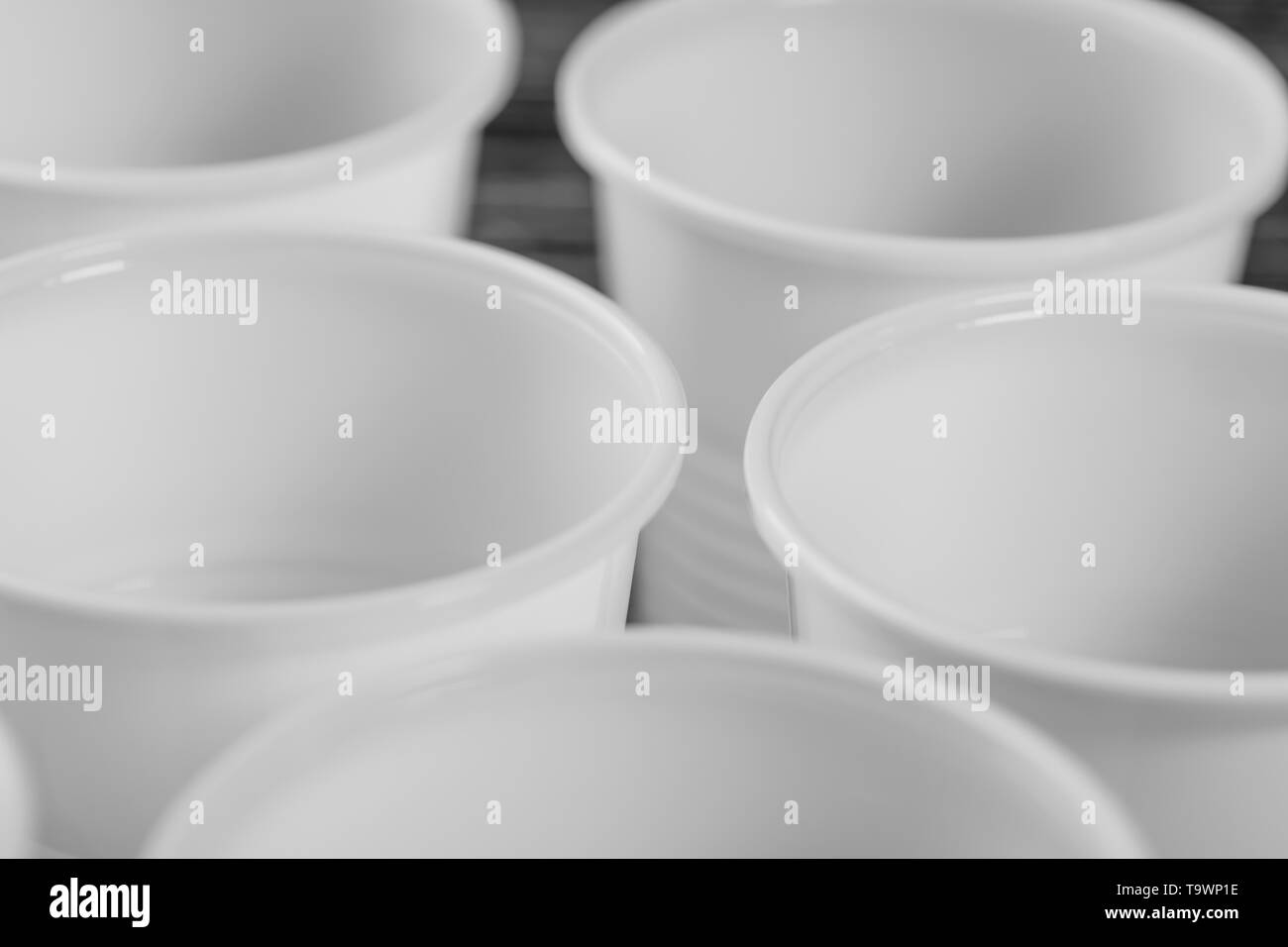 Un groupe de gobelets en plastique blanc fixé sur un tableau noir. Photo gros plan macro Banque D'Images