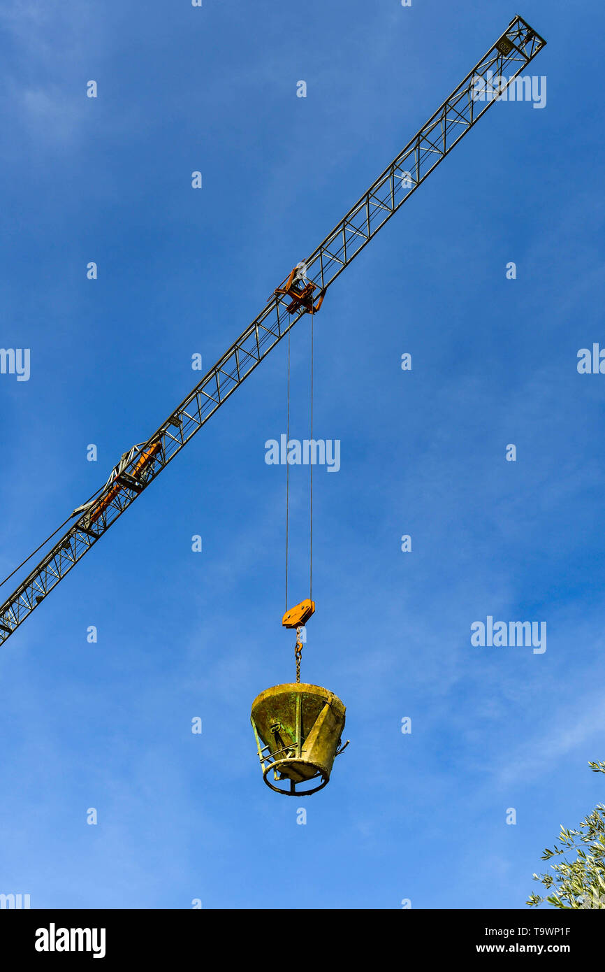 GARDA, Lac de Garde, ITALIE - Septembre 2018 : la descente d'une grue à tour en acier lourd seau de béton sur un chantier dans la ville de Garda, sur le lac de Garde Banque D'Images