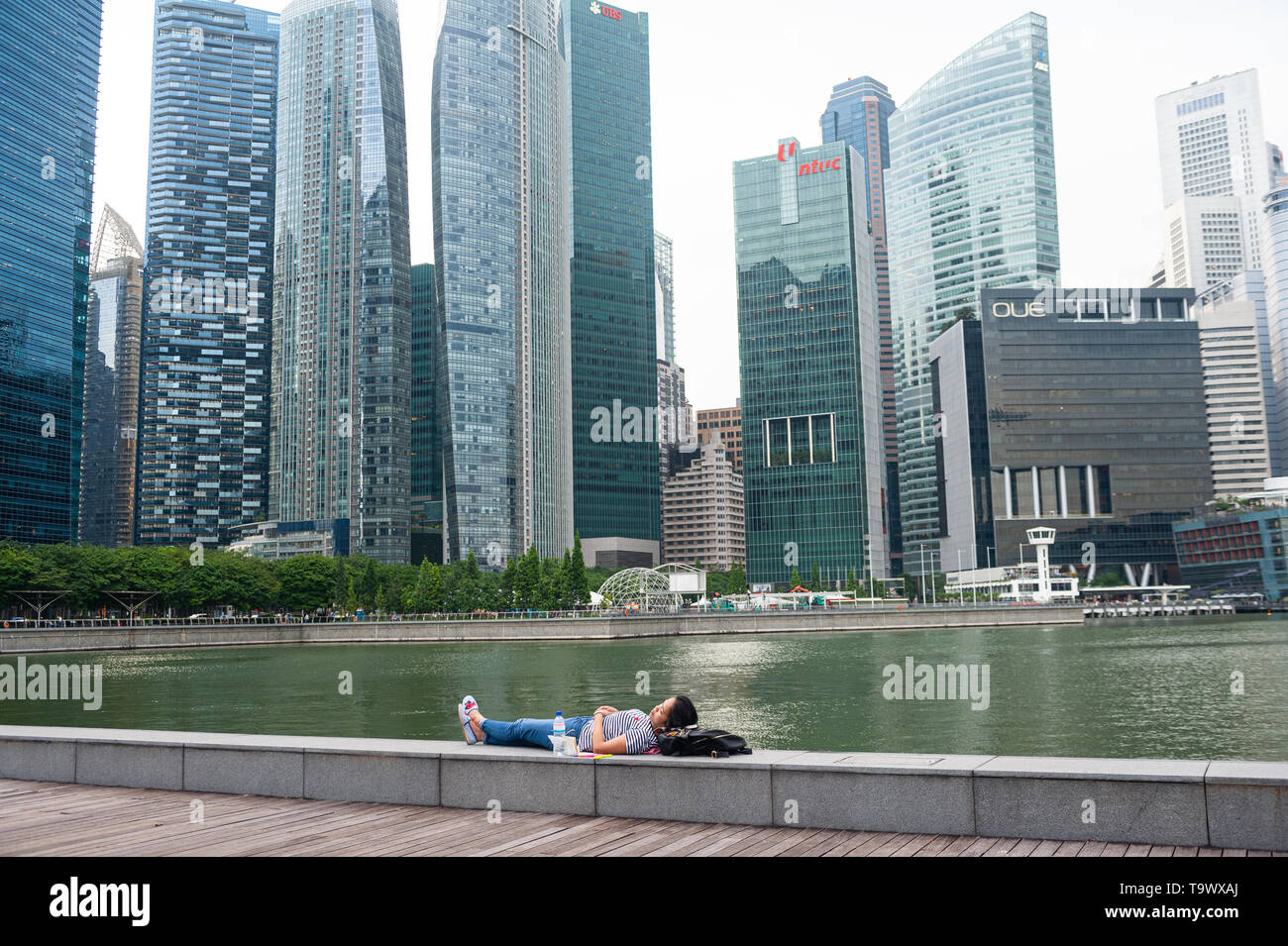 10.05.2019, Singapour, République de Singapour, en Asie - Femme dort à bord de mer dans la baie de Plaisance avant d'horizon de la ville du district commercial central. Banque D'Images