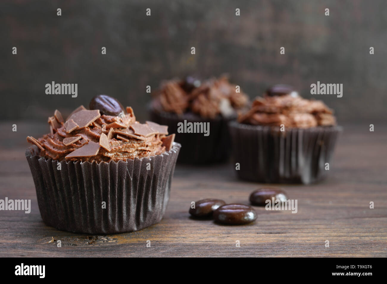 Cupcakes au beurre de cacao brun crème, chocolat et café en grains de bois rustique, copie, espace de discussion sélectionné, la profondeur de champ étroite Banque D'Images