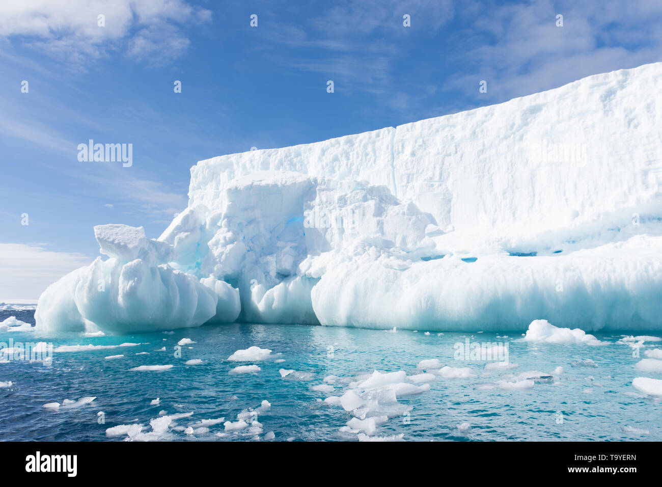 Snowy White iceberg flottant dans l'eau turquoise ou bleu aigue-marine de l'océan Atlantique Sud dans l'Antarctique avec ciel bleu et nuages minces au-dessus. Banque D'Images