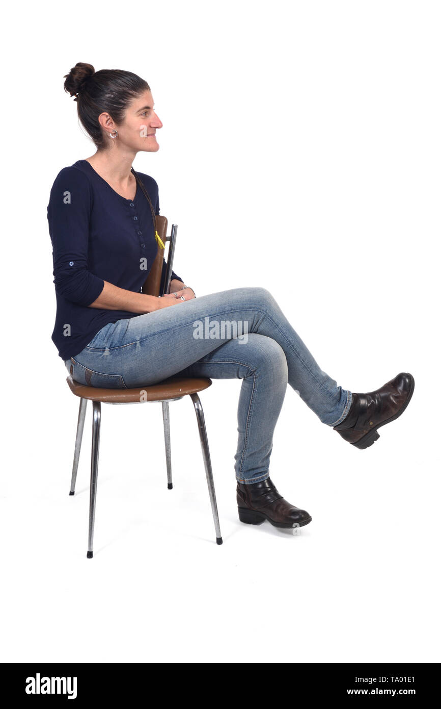 Le portrait d'une femme assise sur une chaise en tailleur et à la recherche  sur le côté sur fond blanc Photo Stock - Alamy