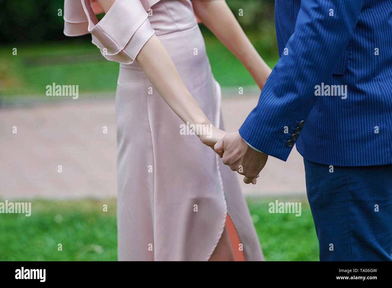 Couple, mariée en robe de satin ivoire et le marié en costume bleu foncé, avec la main un flou, out-of-focus contexte Banque D'Images