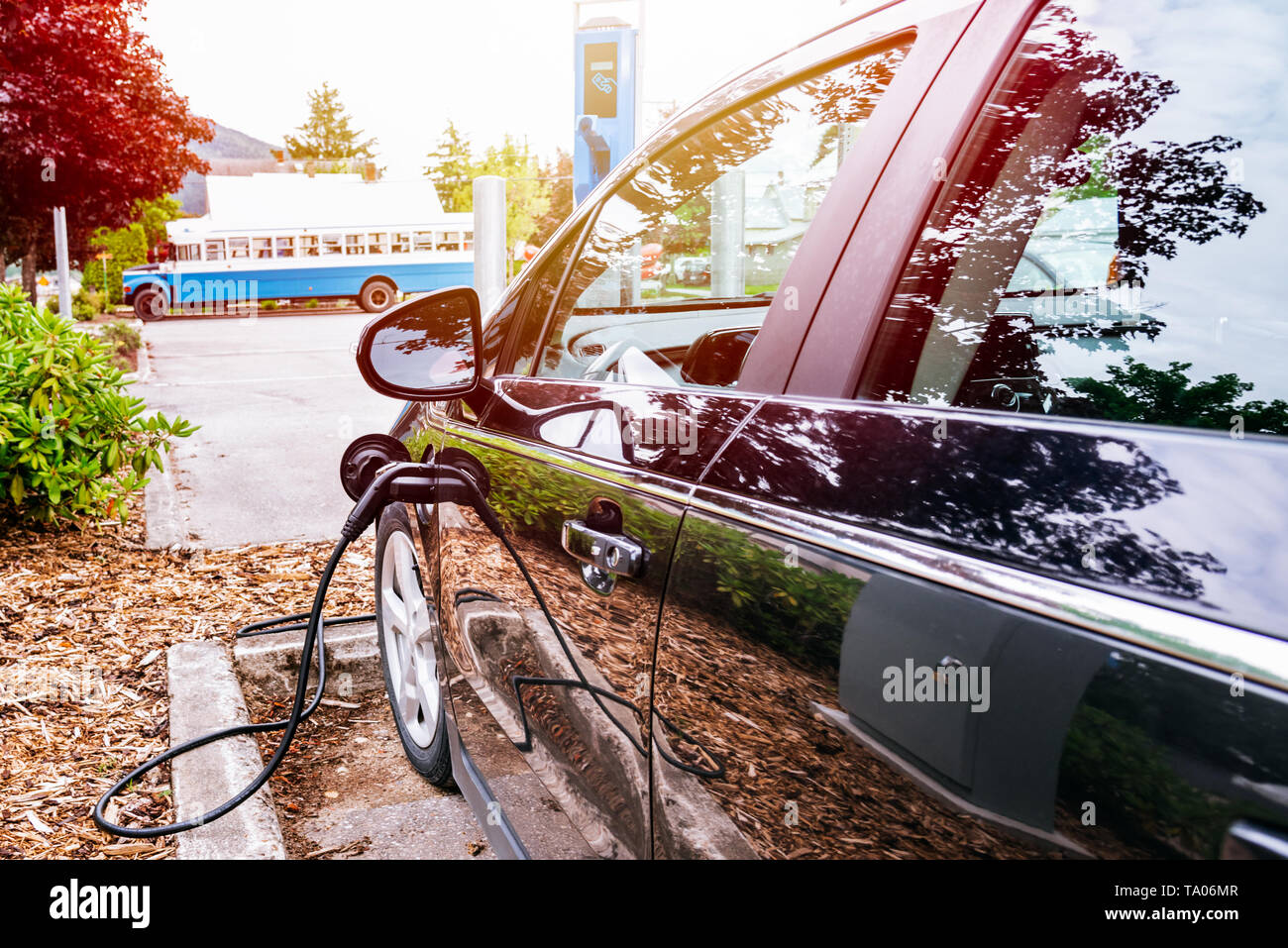 Voiture électrique connecté à un chargeur point dans un parking. Eco-friendly concept d'énergie de remplacement. Banque D'Images