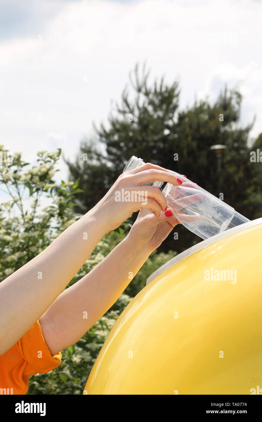 Le recyclage, une femme jette des déchets en plastique dans un récipient jaune Banque D'Images