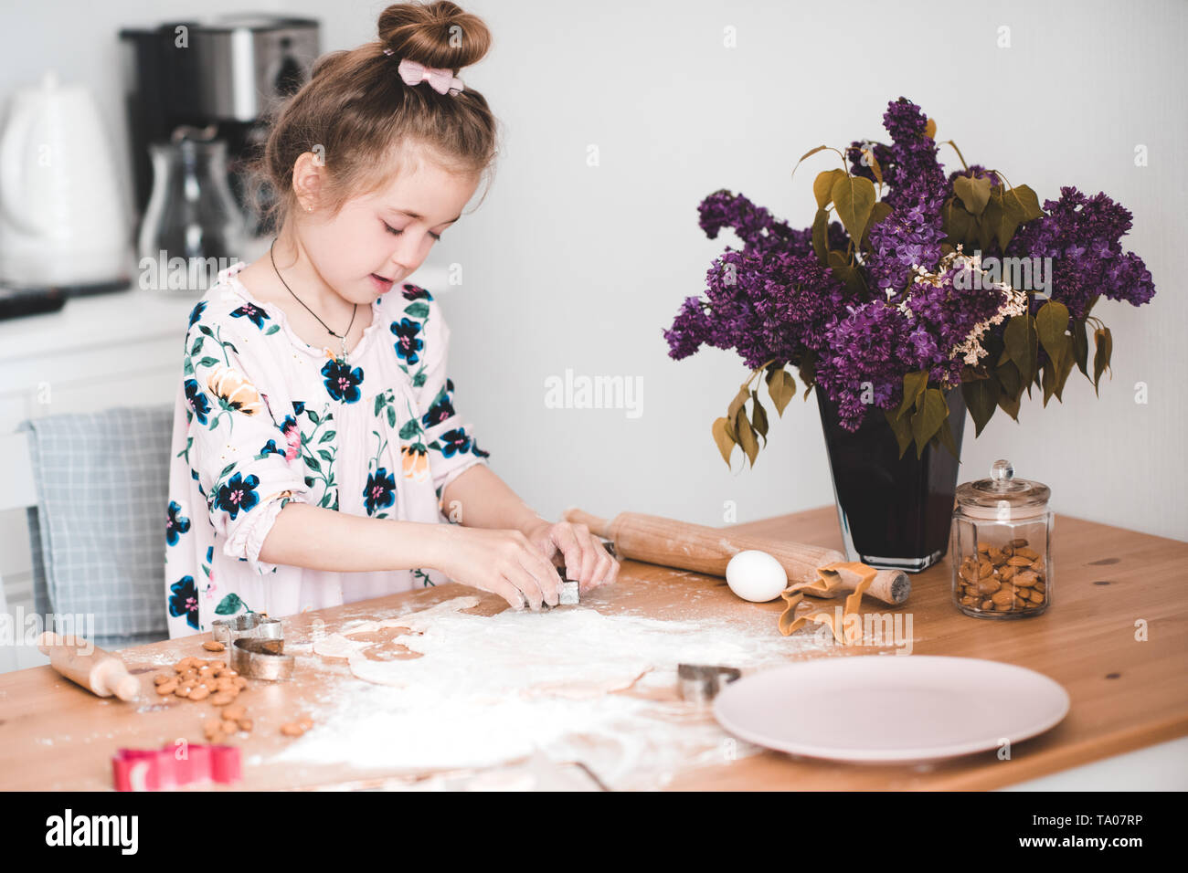 Smiling girl enfant 3-4 ans la cuisson à l'intérieur. Cuisine à des cookies. L'enfance. Banque D'Images