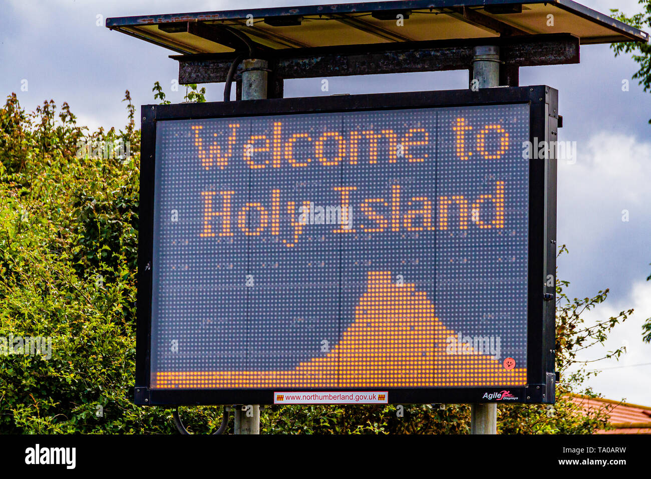 Signalisation routière avertissant les conducteurs de vérifier les temps de passage de la marée et de la sécurité avant de conduire sur le pont-jetée de la marée. Holy Island, Northumberland, Royaume-Uni. Juillet 2018. Banque D'Images