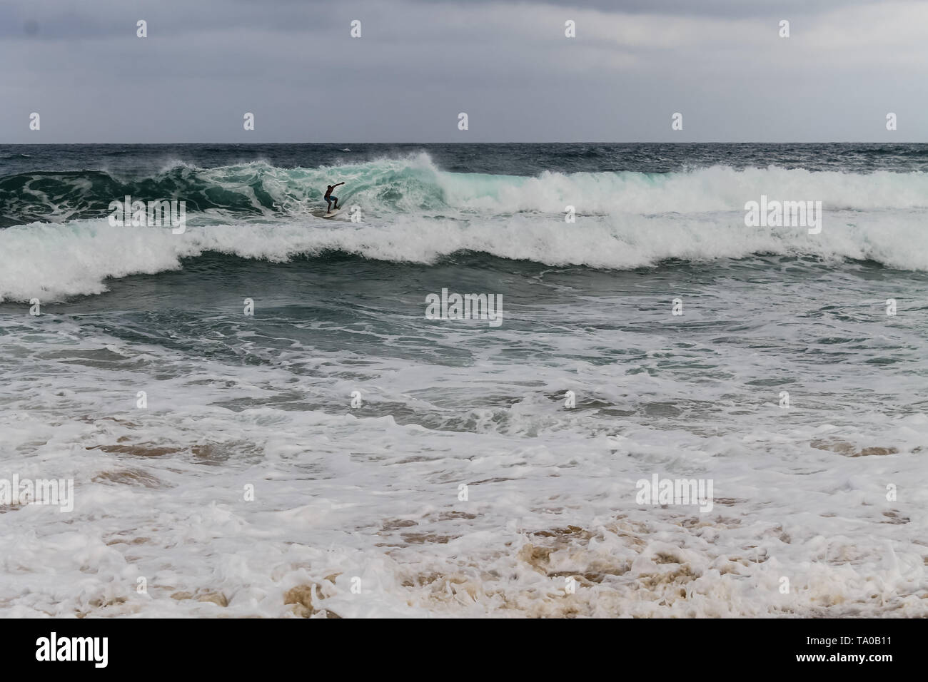 Youn hommes rugueux surf vagues de mousson à Juara Beach sur l'île de Tioman, Malaisie Banque D'Images