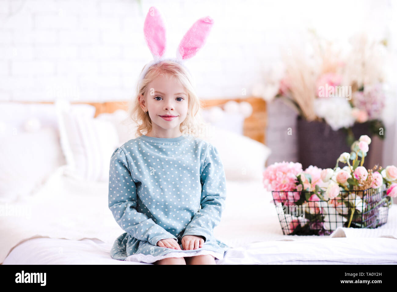 Mignon bébé fille 4-5 ans robe élégante portant des oreilles de lapin et  serre-tête avec fleurs à l'arrière-plan. En regardant la caméra. Temps de  printemps Photo Stock - Alamy