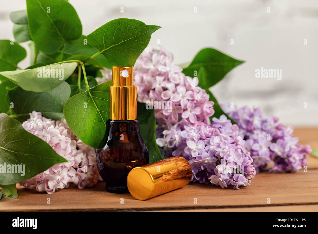 Parfum parfum lilas - Pulvérisateur et fleurs sur table en bois Banque D'Images