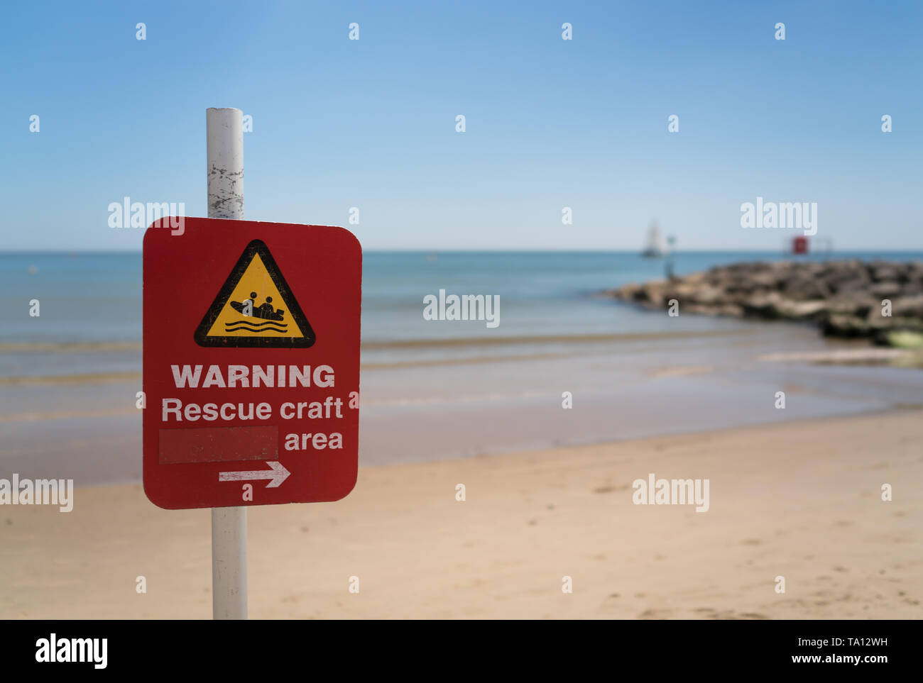 Panneau d'avertissement sur la plage de Sandbanks avec la mer et brise-lames en arrière-plan Banque D'Images