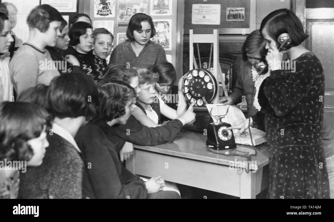 Une classe des filles et se tient assis autour d'une table avec un téléphone et un modèle d'une ligne téléphonique. Une des filles est à l'aide du téléphone, un autre est à la recherche d'un annuaire téléphonique, les autres sont à la recherche au grand cadran. Dans l'arrière-plan sont des affiches, entre autres, des télégrammes de félicitations. La photo a été prise dans le recteur de Postmuseum Hauer au 19ème Volksschule (école élémentaire). Banque D'Images