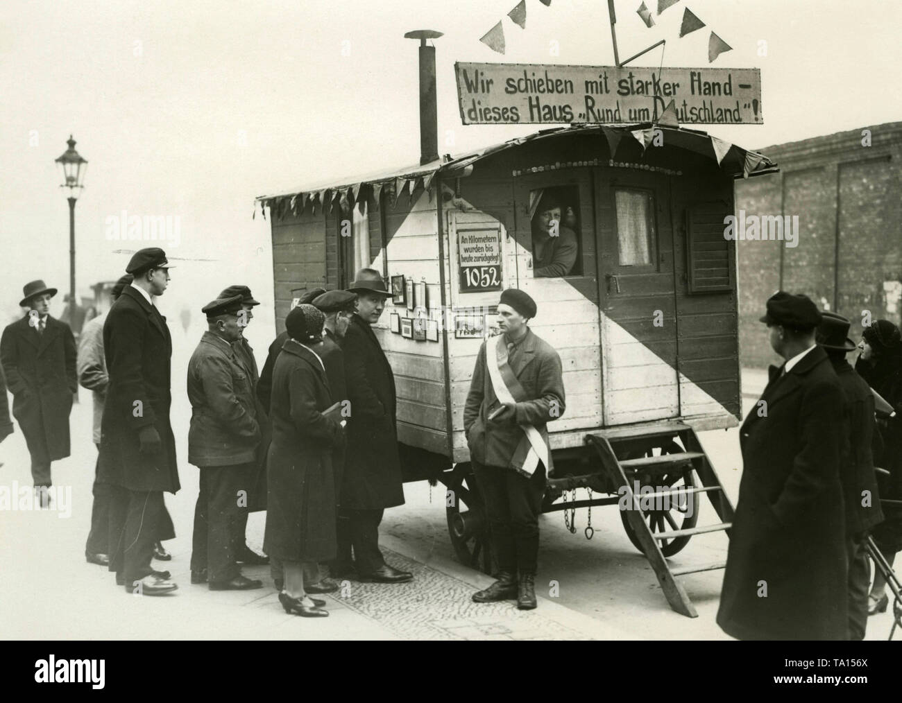 Un homme et une femme aller voyager à travers l'Allemagne avec leur remorque et essayer de recueillir des dons en vendant des cartes postales. Au-dessus de la remorque est un signe avec l'inscription : "Nous pousser la Chambre par l'intermédiaire de l'Allemagne avec une main forte !". Banque D'Images
