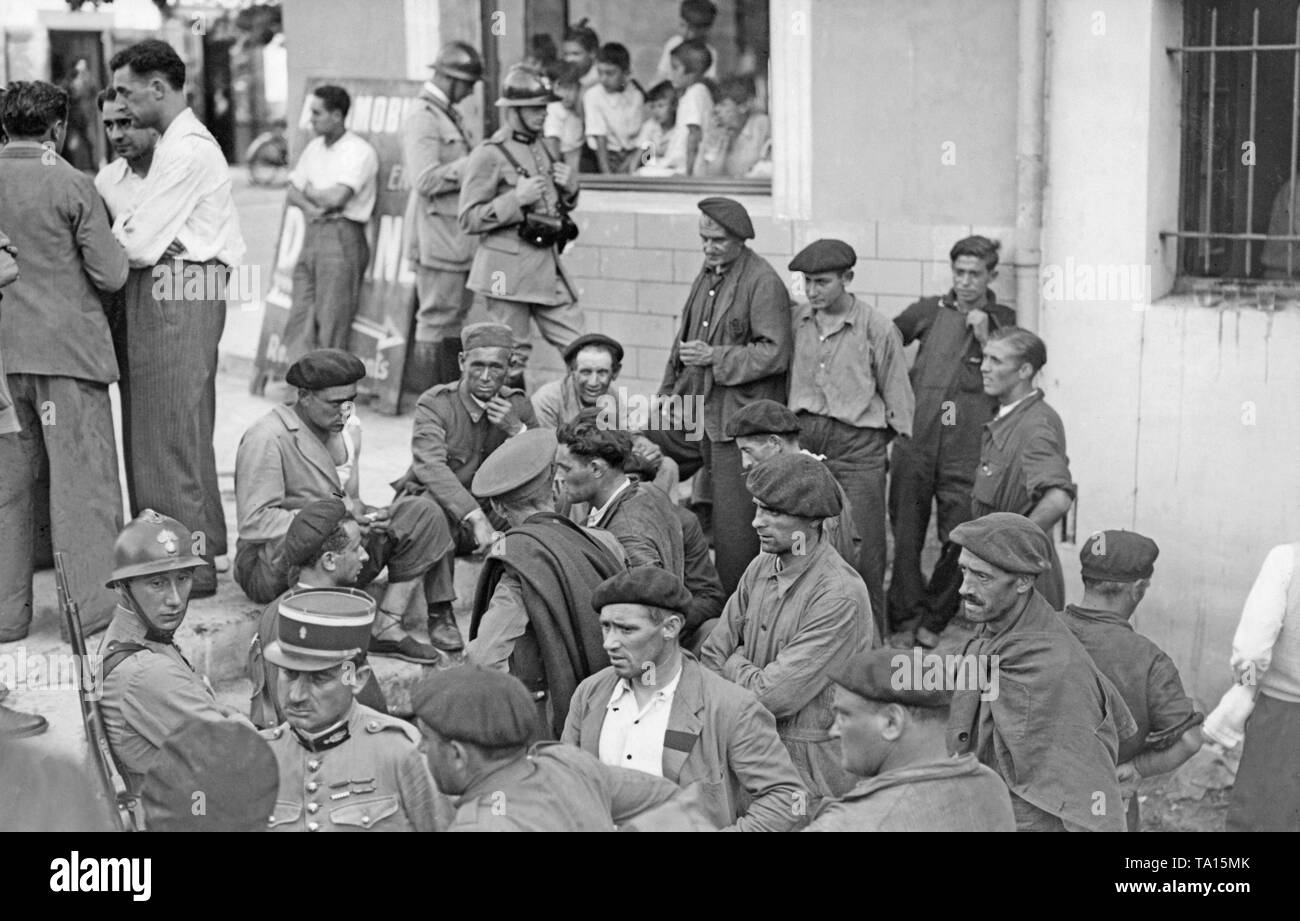 Soldats français prennent soin soins d'un groupe d'Espagnols (assis, enveloppés dans des couvertures avec bouchons basque, en partie dans l'uniforme de l'armée espagnole), qui ont déjà fui les troupes du général Franco, dans la petite ville des Pyrénées françaises de St-Jean-Pied-de-Port, l'Aquitaine en septembre, 1936. San Sebastian a été envahi par les nationalistes, déjà en juillet. Banque D'Images