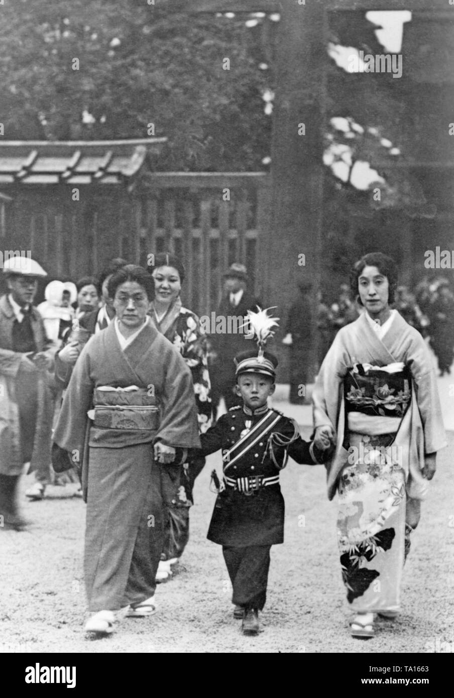 Deux femmes et un garçon d'accéder à une nouvelle année, la prière dans le culte de l'empereur Meiji à Tokyo. Le garçon est déguisé en soldat. Banque D'Images