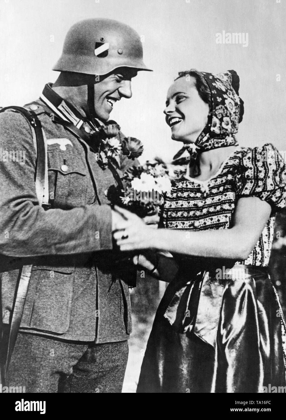 En mars, des troupes allemandes au cours de l'annexion de l'Autriche à l'Empire allemand. Un soldat allemand reçoit des fleurs d'une jeune femme. Banque D'Images