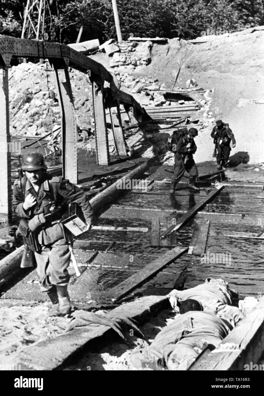 Trois soldats allemands d'une équipe radio traverser un pont détruit sur le front de l'Est (Lieu inconnu, probablement dans le Belarus). En plus des débris, des soldats soviétiques morts gisent sur le reste du pont. Photo de l'entreprise de propagande (PK) : correspondant de guerre Weber. Banque D'Images