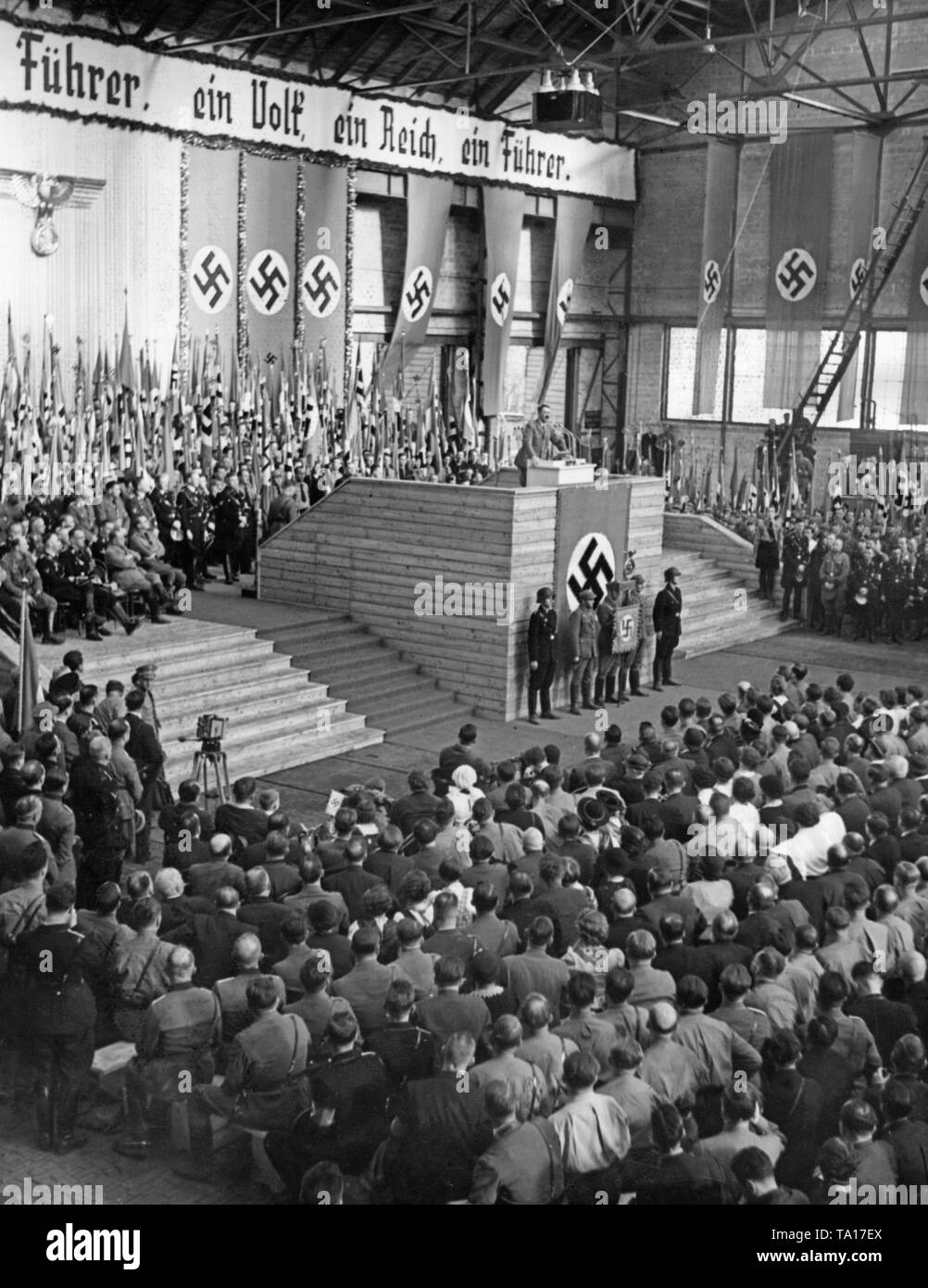 Le dictateur nazi Adolf Hitler est titulaire d'un discours dans une salle de l'Wagon Weitzer Werke à Graz à l'occasion de l'annexion de l'Autriche à l'Empire allemand. Au-dessus de la scène : 'une nation, un Reich, un Führer.' Banque D'Images