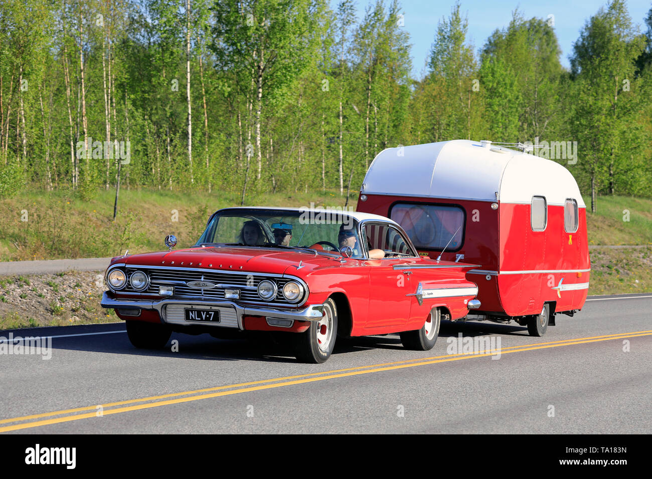 Salo, Finlande. Le 18 mai 2019. Classic 1960 Chevrolet Impala Convertible rouge avec une caravane vintage sur l'autoroute sur Maisema 2019 Salon de croisière. Banque D'Images