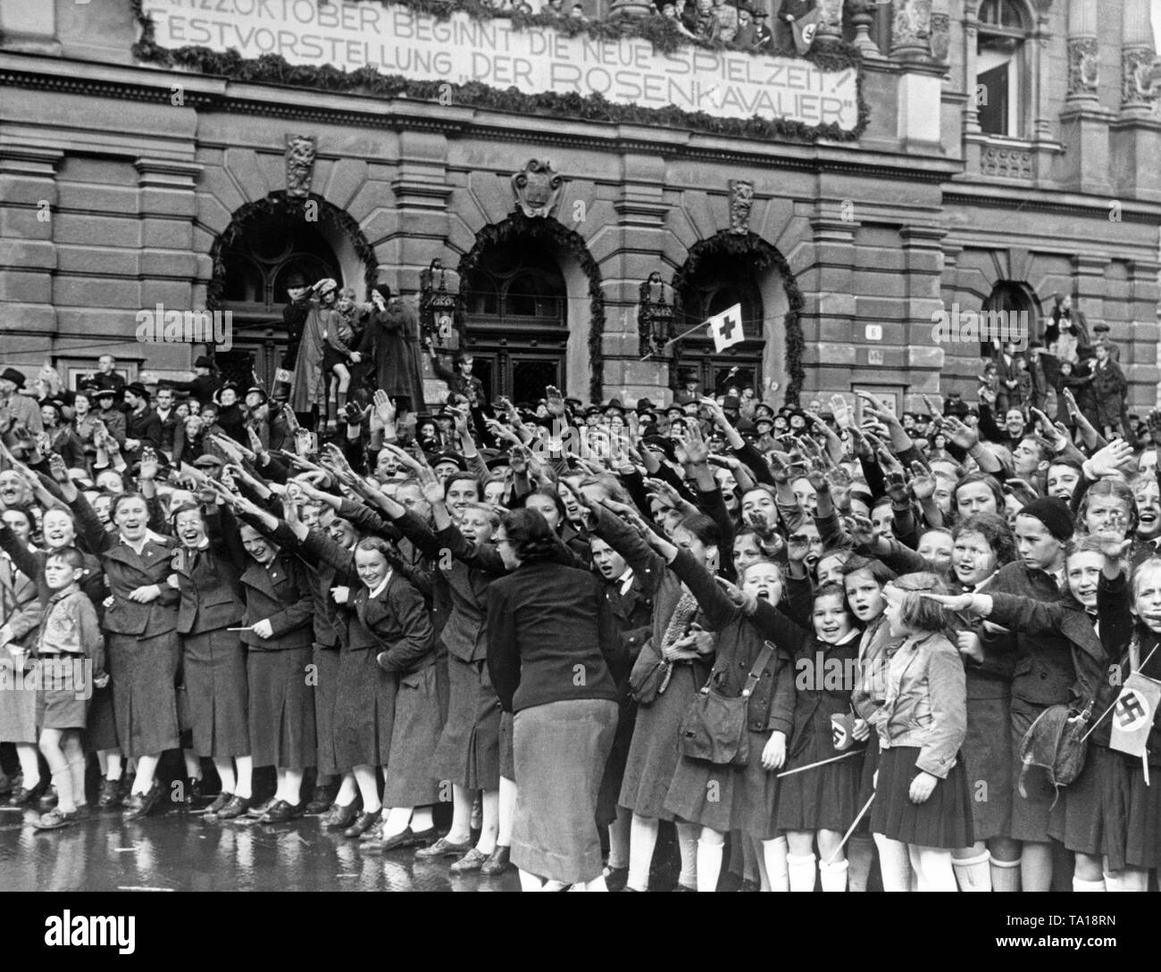 La population de Reichenberg (aujourd'hui Liberec) Bienvenue à la marche des troupes en face du théâtre de la ville le 9 octobre, 1938. Au-dessus de l'entrée du théâtre, un panneau avec l'inscription : "La nouvelle saison commence le 22 octobre ! Gala "Der Rosenkavalier". Banque D'Images