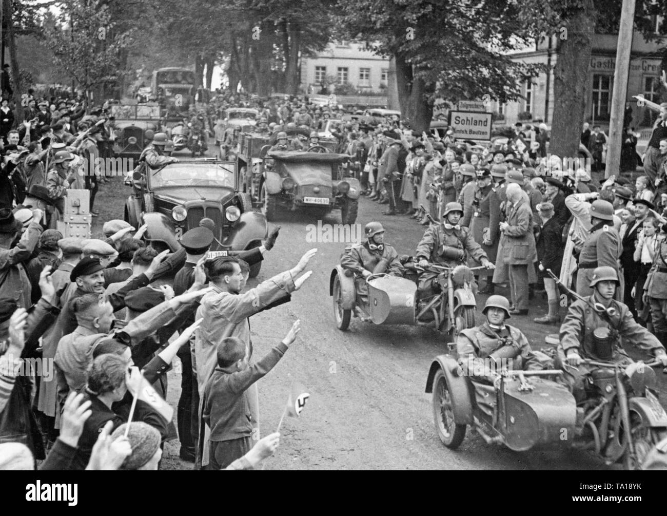 Une unité motorisée de troupes allemandes traverse l'ancienne frontière à German-Czechoslovak Schluckenau (aujourd'hui Sluknov) le 2 octobre, 1938. Les gens saluer les soldats avec le salut nazi. Banque D'Images