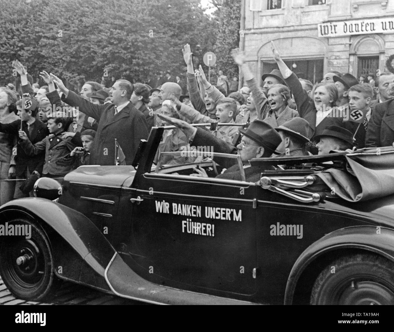 Les habitants d'une ville dans les territoires Sudètes (Zone II) salue les troupes en retraite avec le salut nazi le 2 octobre 1938. Au premier plan, une voiture avec l'inscription : "Nous remercions notre Führer !' Banque D'Images