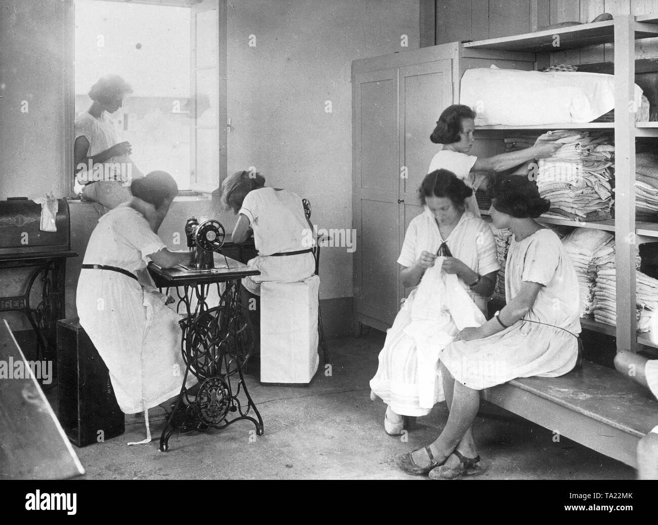 Six femmes travaillent dans un atelier de tailleur de vêtements d'enfants dans une colonie juive. Banque D'Images