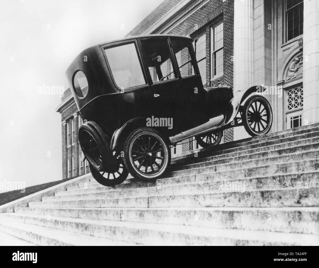 Afin d'appuyer le slogan "Le modèle T durs partout" devant la cour, un employé de Ford conduit un 'Tin Lizzy' sur un escalier directement en face de l'entrée de la Cour des bâtiments. Banque D'Images