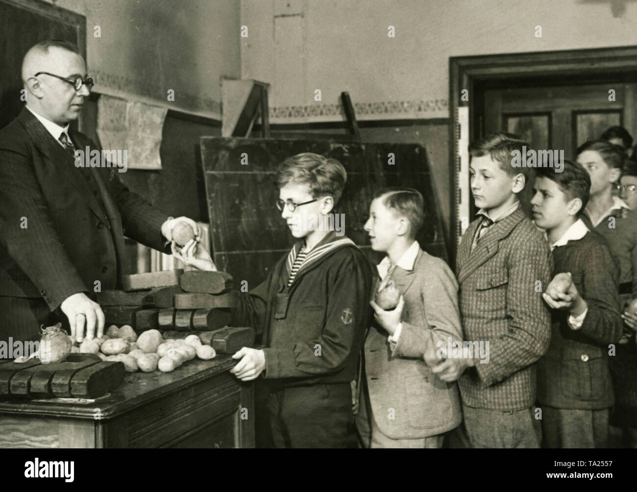 Les élèves de l'Berlin Kaiser-Friedrich-Schule faites un don chaque jour soit une pomme de terre ou un morceau de charbon de bois pressé, qui sont recueillis par l'école et transmise à l'Winterhilfswerk. La photo montre la collecte de dons par l'enseignant avant le début de la leçon. Banque D'Images