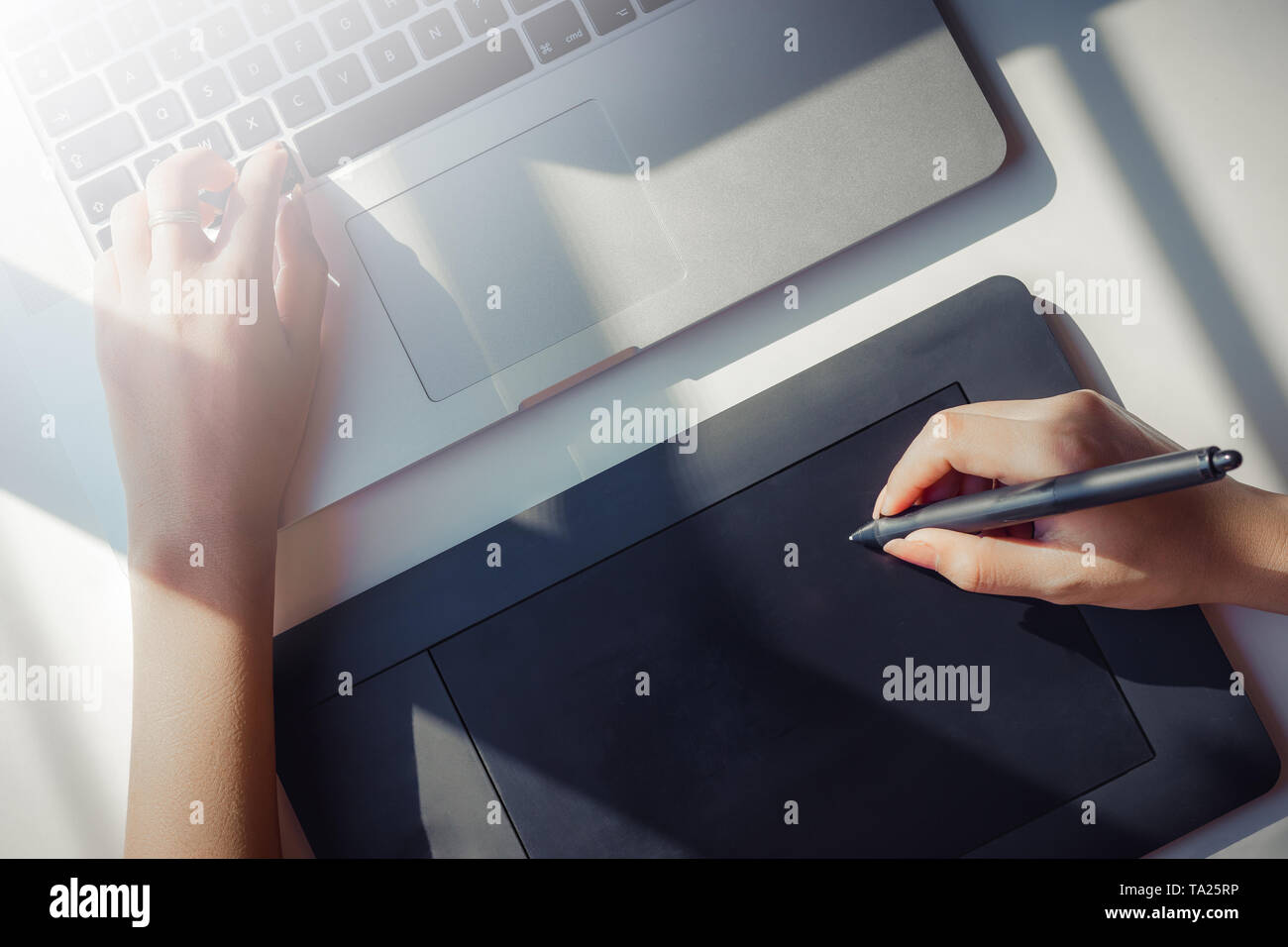 Graphic Designer using digital tablet et ordinateur portable avec la lumière du soleil Banque D'Images
