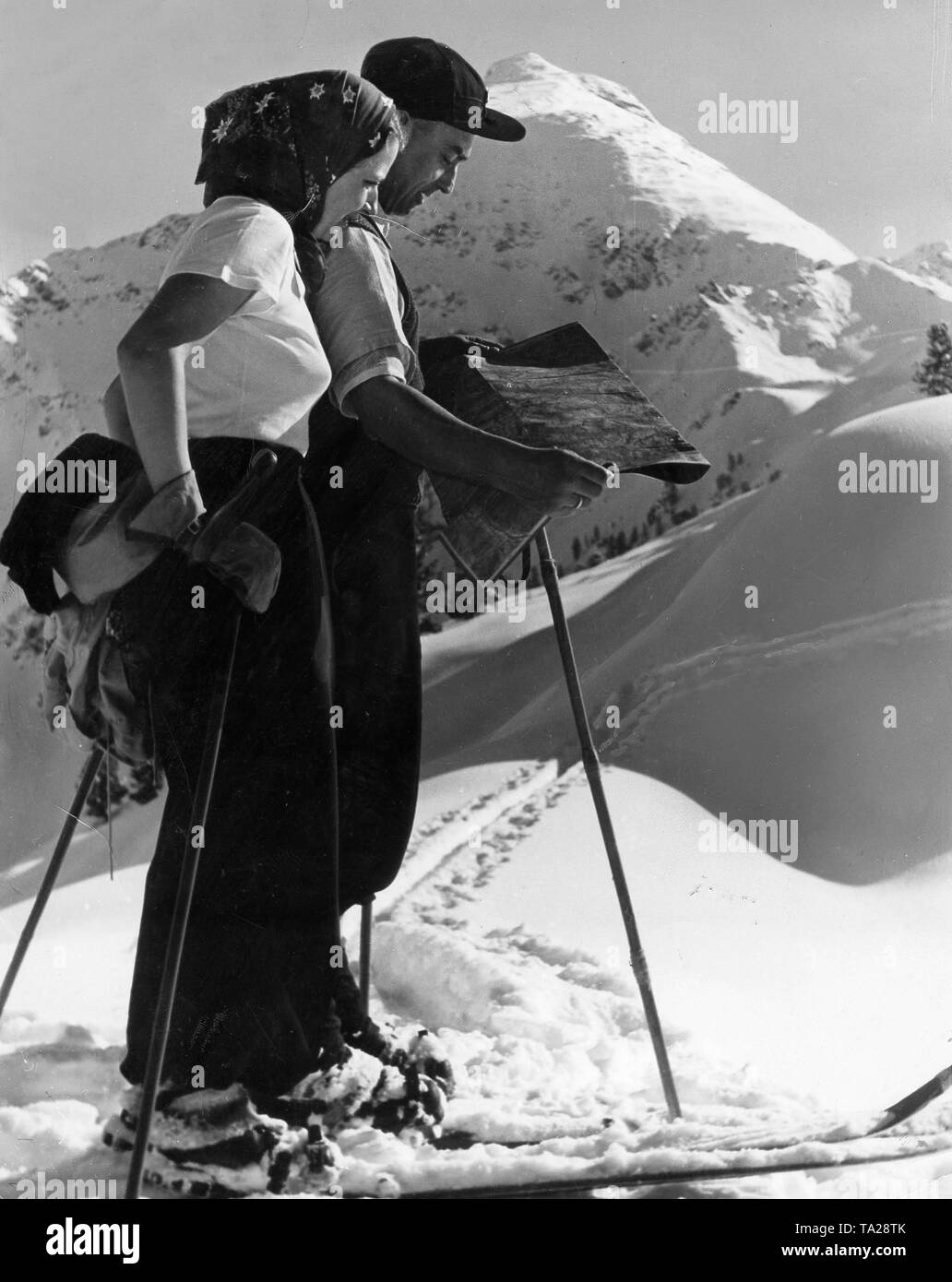 Un homme et une femme en skis dans les montagnes enneigées s'orienter à l'aide d'une carte Banque D'Images