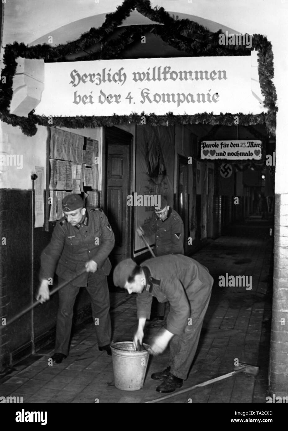Les soldats de la quatrième compagnie nettoyer les chambres des casernes à l'occasion de la prochaine Journée de la Wehrmacht. Au-dessus de l'entrée, une bannière avec l'inscription 'Bienvenue à la 4e Compagnie". Probablement à Berlin. Photo : Schwahn. Banque D'Images
