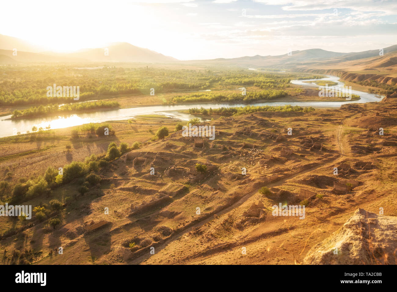 Beau paysage dans la lumière du soleil en contre-jour. Mtkvari River sur l'arrière-plan des montagnes du Caucase, sur les rives de la rivière ruines d'une cité médiévale sett Banque D'Images