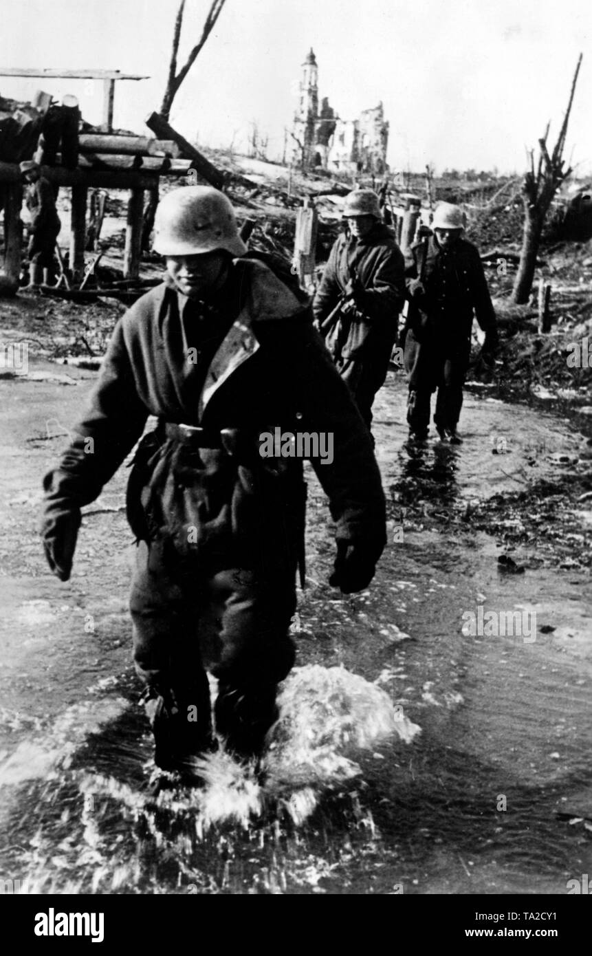 Les soldats allemands patauger dans une plaine d'inondation inondé dans la petite ville de Velizh à environ 130 km au nord-ouest de Smolensk. Dans l'arrière-plan, une église en ruine. En raison de la fonte des neiges au printemps, les soldats sont aux prises avec la boue et l'eau sur l'ensemble du Front de l'Est. Photo de l'entreprise de propagande (PK) : correspondant de guerre Hermann. Banque D'Images