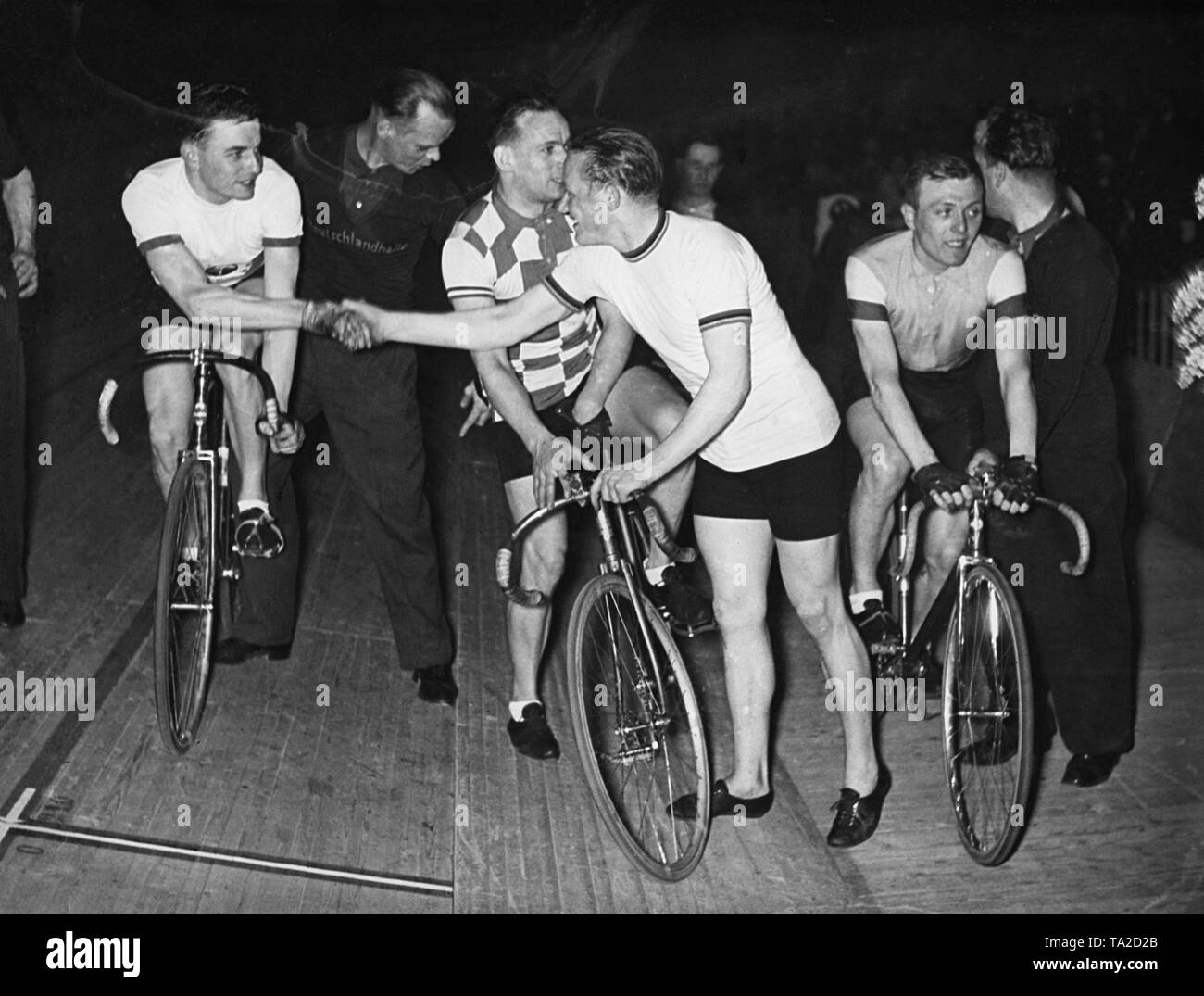 Les deux-temps champion cycliste allemand en sprint, champion du monde 1935 et champion olympique de 1936 Toni Merkens félicite son concurrent victorieux Richard de France à l'omnium de la race en 1937 dans la Deutschlandhalle à Berlin. Entre les deux, le Pecyueux français. Sur la droite, l'Huys belge. Banque D'Images