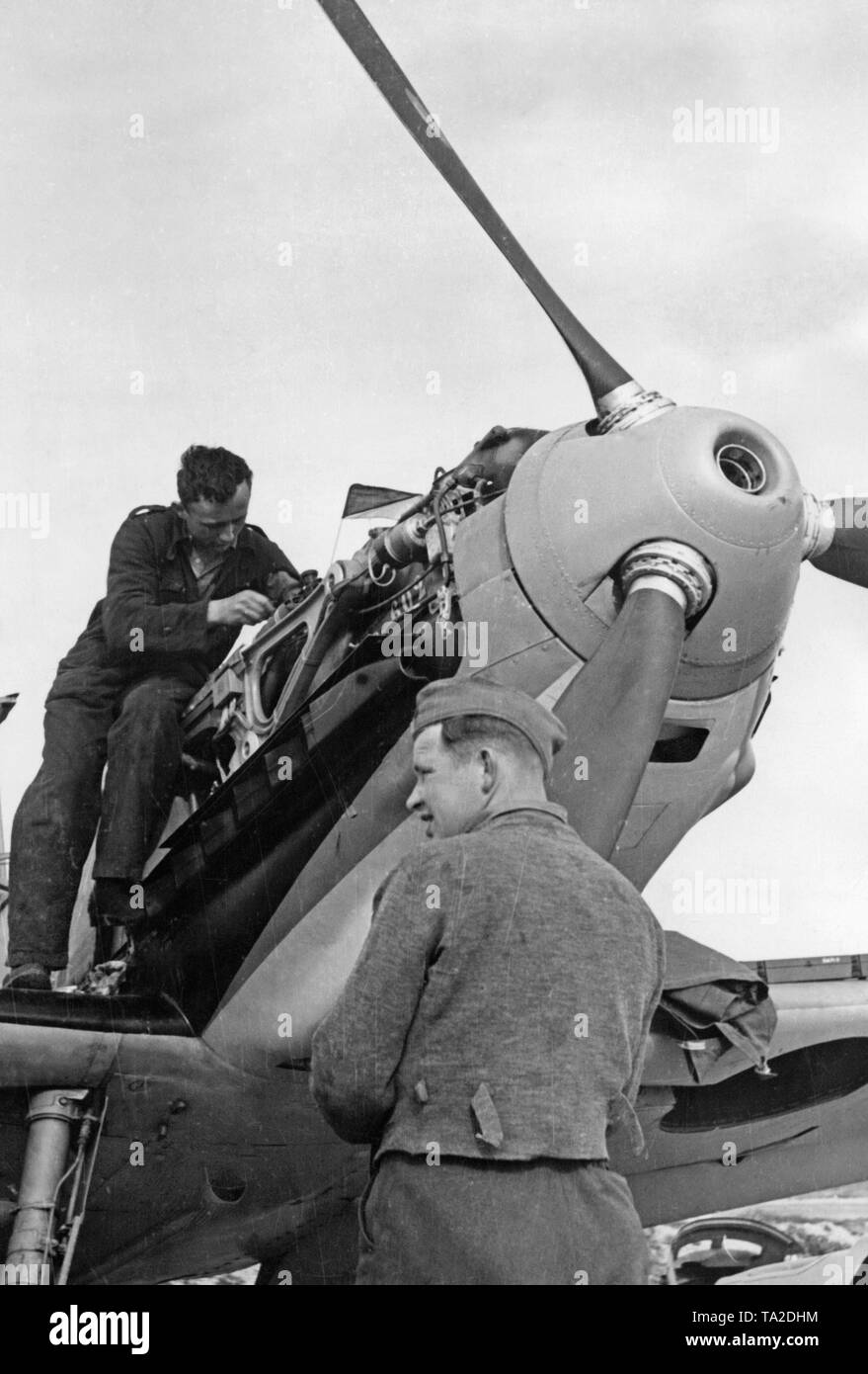 Photo de deux mécaniciens de la Luftwaffe pendant la réparation du moteur d'un Messerschmitt Bf 109 B-series à un aérodrome en Espagne. Ici, le canon de la mitrailleuse dans le creux du nez de l'hélice. Banque D'Images