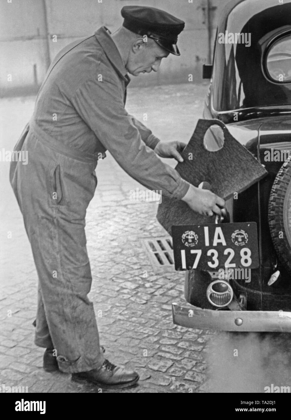 Un préposé de station met une protection de remplissage autour de la goulotte de remplissage avant de faire le plein, afin de protéger la peinture de dommages causés par débordement de l'essence. Banque D'Images