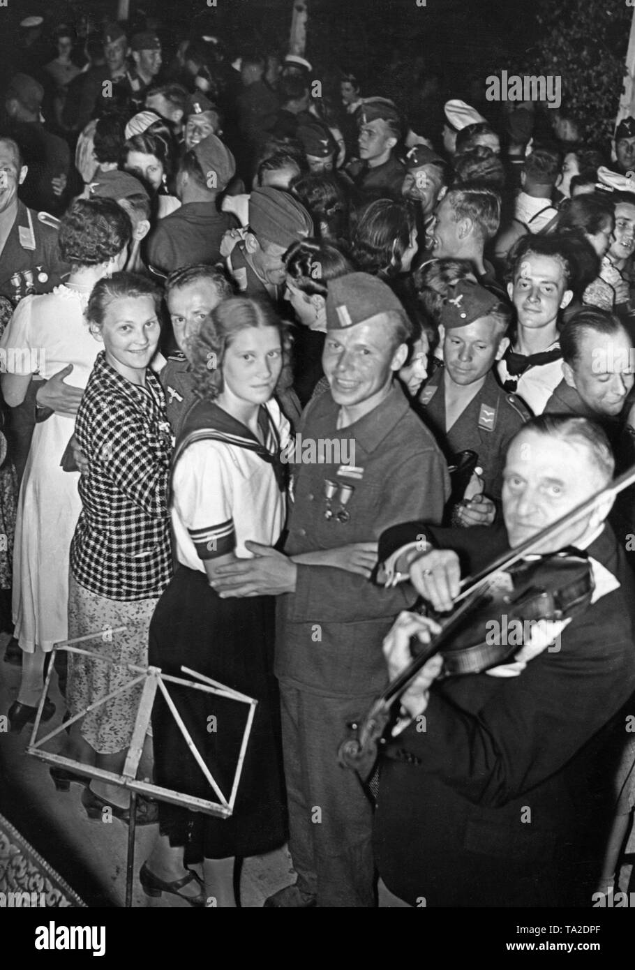 Photo d'un groupe de soldats de la légion Condor (l'armée et la force aérienne) et les femmes en uniforme de Berlin pendant une danse après la revue de la victoire de la troupe à Mitte (Berlin) dans la soirée du 6 juin 1939, à Doeberitz. Le joyeux bivouac était organisée par la Légion et le NSG "Kraft durch Freude". Il y avait un feu de bivouac, des spectacles en plein air et feu d'artifice. Un violoniste est au premier plan. Banque D'Images