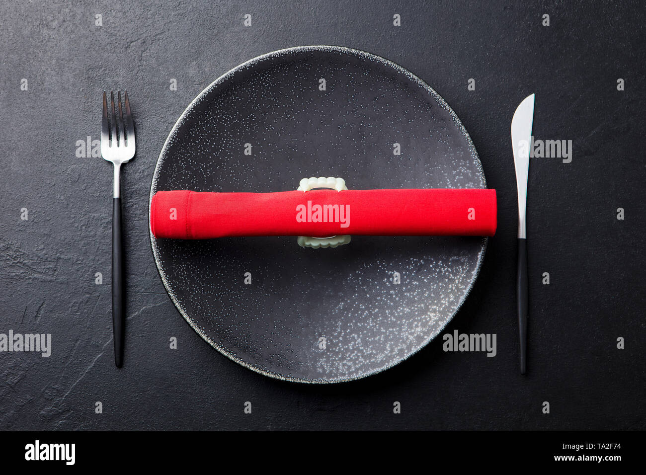 Halloween de la table, décoration avec des dents de vampire et serviette rouge. Arrière-plan en ardoise noire. Vue d'en haut. Banque D'Images