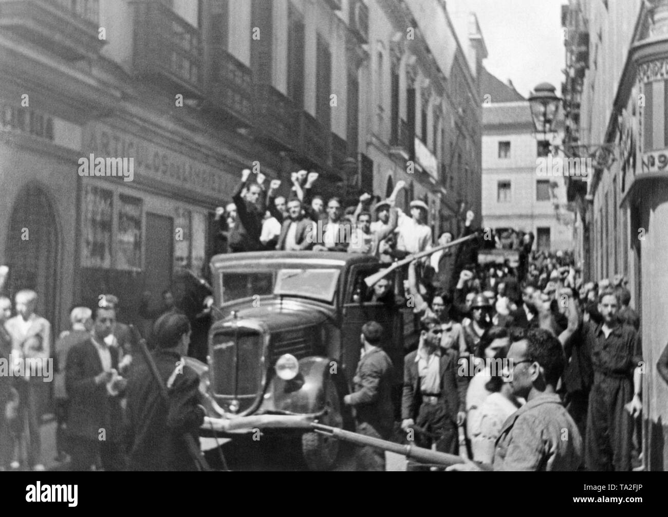 Photo de combattants républicains volontaire joyeuse du Front Populaire et de la milice des travailleurs voyageant dans un camion à travers une ville en Catalogne, Espagne. Dans les jours après le déclenchement de la guerre civile, de nombreuses garnisons de l'armée rejoint les putschistes du général Franco. Après le déclenchement de la guerre civile le 17 juin 1936, de nombreuses villes en Espagne ont été le théâtre de combats de rue entre républicains, communistes et nationalistes. Banque D'Images