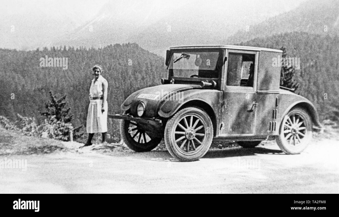 Femme à côté d'une petite voiture d'Hanomag AG, nommé 'Kommissbrot" en raison de sa forme inhabituelle, d'une visite guidée sur le col de Fern. Banque D'Images