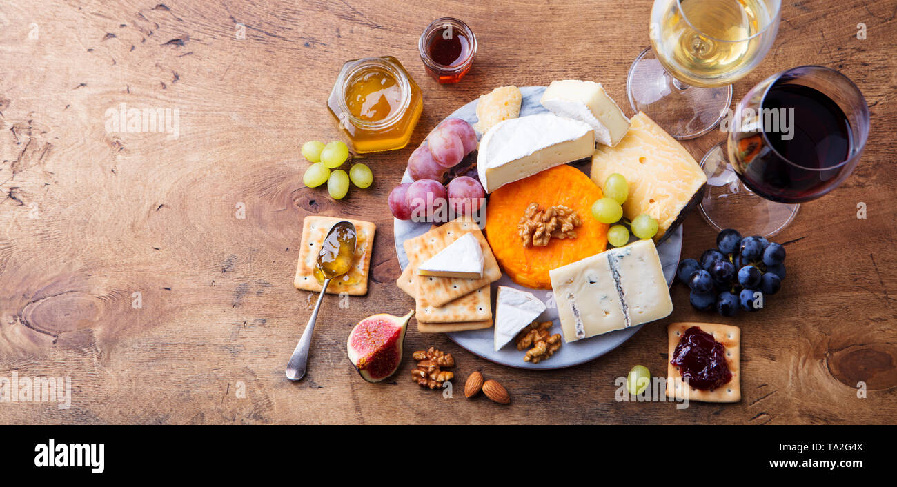 Assortiment de fromage avec du vin rouge et blanc dans les verres. Fond de bois. Vue d'en haut. Copier l'espace. Banque D'Images