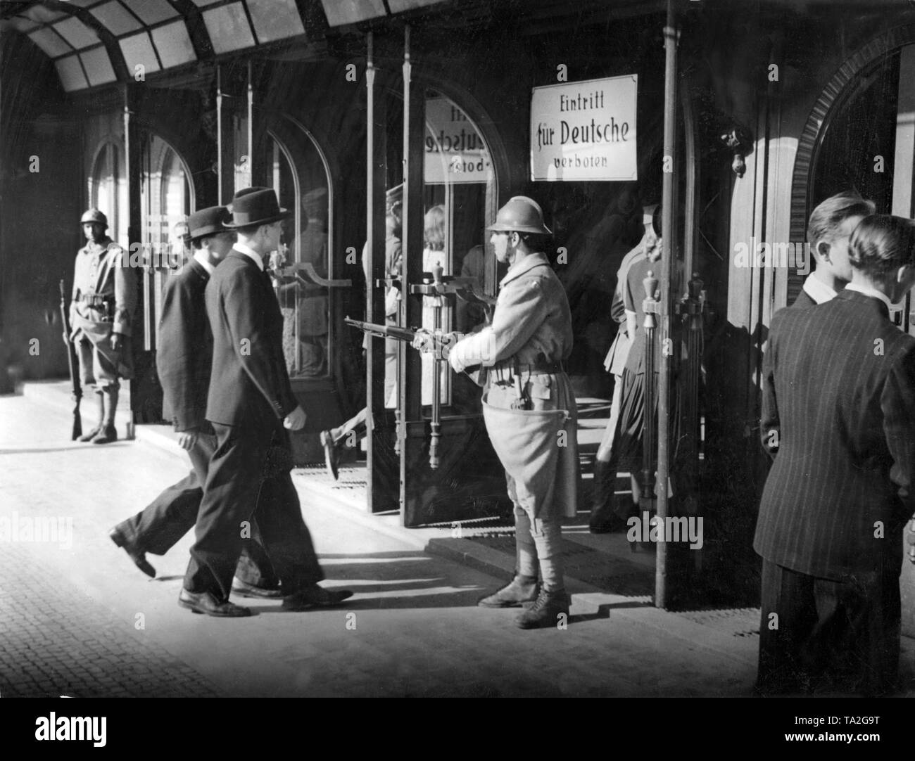 Un soldat de l'armée française qui garde l'entrée d'un bâtiment avec une carabine. Sur un panneau il est dit : l'admission pour les Allemands interdit. Probablement une scène d'un film. Banque D'Images