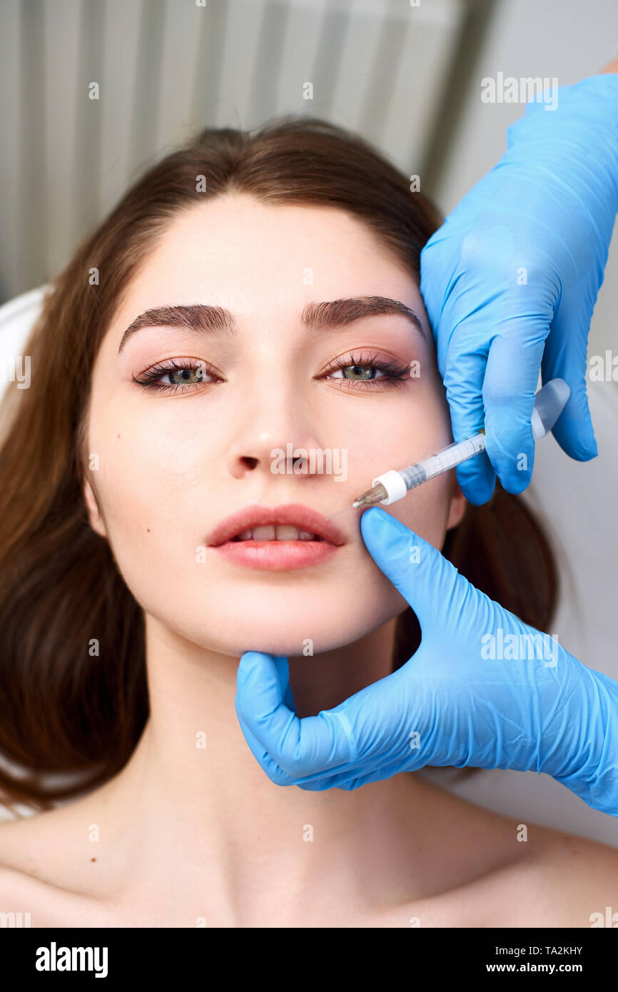 L'augmentation des lèvres. Belle Jeune femme recevant la bouche d'injection d'acide hyaluronique. Esthéticienne médecin faisant mains libre Procédure Beauté à femelle Banque D'Images