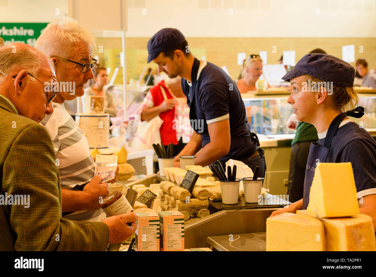 Les personnes travaillant sur la vente de décrochage fromage assortiment de fromages (femelle trader parler aux clients potentiels) -Grand Show Yorkshire, Harrogate, England, UK Banque D'Images