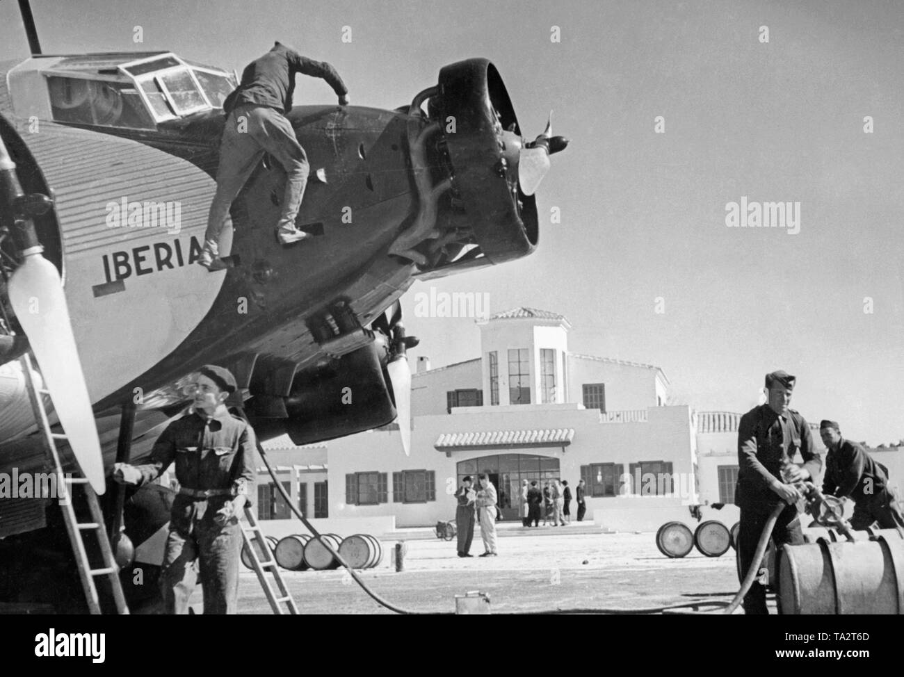 Photo des postes de pilotage et d'un Allemand moteurs Junkers Ju 52 de la compagnie aérienne espagnole Iberia 1939 à l'aéroport de Salamanque, Castille et Leon, Espagne. Les mécaniciens travaillant sur l'un des moteurs. La machine est nommé 'ola', après que le général Emilio Mola Vidal (mort en 1937), l'un des dirigeants du soulèvement du Général Francisco Franco. Pendant la guerre civile, la Deutsche Lufthansa et l'Ibérie (fondée en 1927) a effectué des vols principalement avec les pilotes allemands dans la zone nationale espagnole à partir de 1937. L'aéronef ont été fournies par la Deutsche Lufthansa AG. Banque D'Images